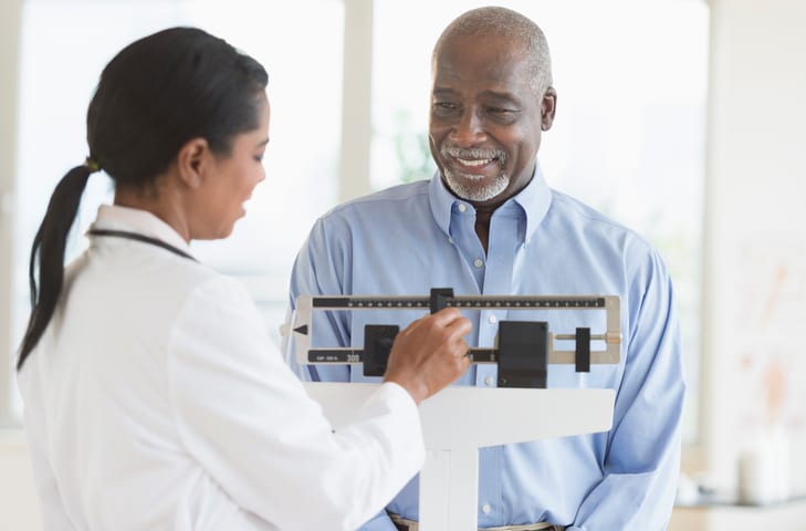Black doctor weighing patient